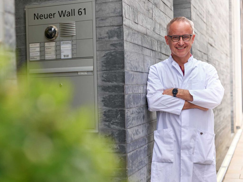 Stehendes Portrait von Prof. Dr. Martin Stieve in seiner HNO Privatpraxis in Hamburg, er steht draußen an der Praxismauer