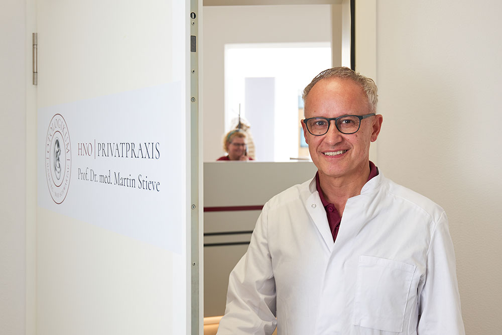 Stehendes Portrait von Prof. Dr. Martin Stieve in seiner HNO Privatpraxis in Hamburg, er steht in einer Tür.