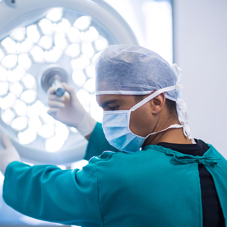 Das Bild zeigt einen Arzt bei einer HNO-Operation im OP mit Maske und Kittel