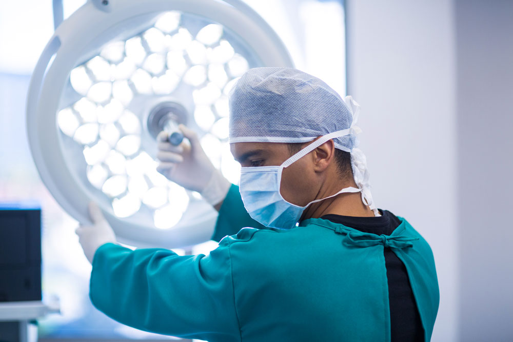 Das Bild zeigt einen Arzt bei einer HNO-Operation im OP mit Maske und Kittel