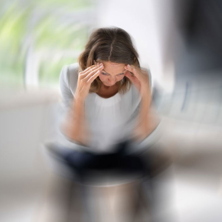 Das Bild zeigt eine Frau die auf dem Sofa sitzt und man wird wie ein Tunnel zu ihr geführt, das Bild zeigt Schwindel